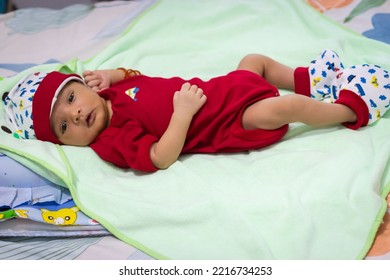 Cute Newborn Baby Looking At Camera In Red Dress From Different Angle