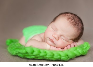 Cute Newborn Baby On A Green Chunky Knit Blanket