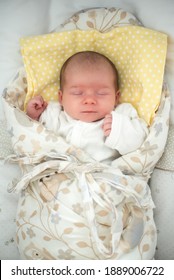 Cute Newborn Baby Sleeping In Swaddle Wrap With Smile On Her Face. Newborn Theme