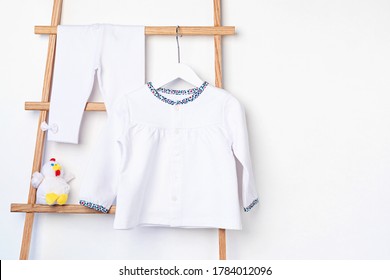 Cute Newborn Clothes Hanging On The Rack. Organic Cotton Baby Apparel Mockup.