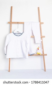 Cute Newborn Clothes Hanging On The Rack. Organic Cotton Baby Apparel Mockup.