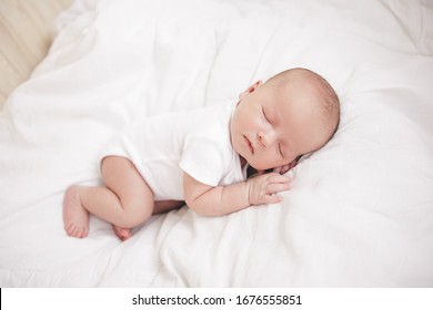 cute newborn sleeping boy on a white bed