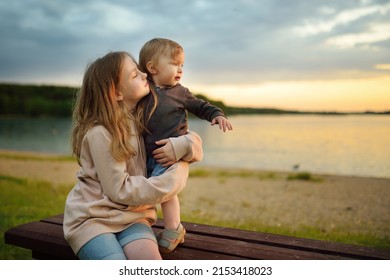 Cute Older Sister Cuddling With Her Toddler Brother. Adorable Girl Holding Baby Boy. Children With Large Age Gap. Big Age Difference Between Siblings.