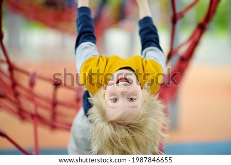 Cute perky preschooler boy having fun on outdoor playground. Spring or summer or autumn active sport leisure for kids. Outdoor activities for family with children.