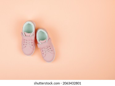 Cute Pink Children's Sneakers. Orange Background. Baby Clothes And Shoes. Flatlay,copy Space