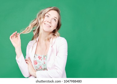 Cute playful young woman with beautiful eyes and charming mysterious smile, touching her blond wavy hai , having flirting look. Attractive gorgeous lady smiling broadly, posing at greem studio wall. - Powered by Shutterstock