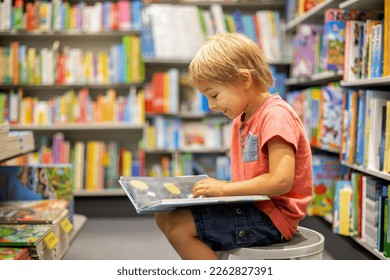 Cute preschool child, sitting in a bookstore, looking at books on summer day - Powered by Shutterstock