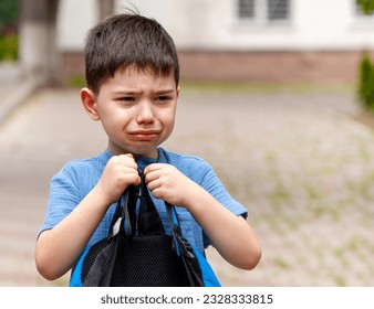 cute preschooler boy crying in classroom or outside with backpack in hands.dissatisfied unhappy sad upset angry kid child.back to school autumn time.yellow interior.tears on check. - Powered by Shutterstock