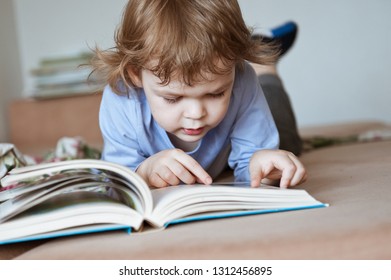 Cute preschooler boy reading a book with interest.