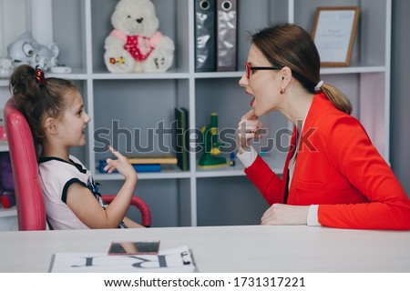 Cute preschooler little kid girl speaking practicing sounds articulation during private lesson with parent mom or speech language therapist teacher. Voice problem and pronunciation learning concept