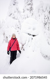 Cute pre-teen girl next to funny snow ghost tree in winter forest in Lapland Finland