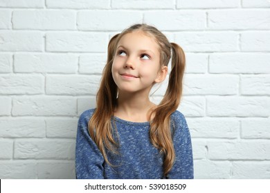 Cute pretty girl near light brick wall