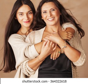linda y bonita hija adolescente con madura abrazo de madre, maquillaje de brunette estilo moda, colores cálidos Foto de stock