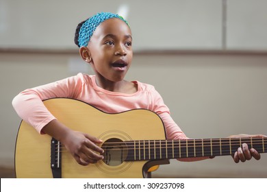 Cute Pupil Singing And Playing Guitar In A Classroom In School