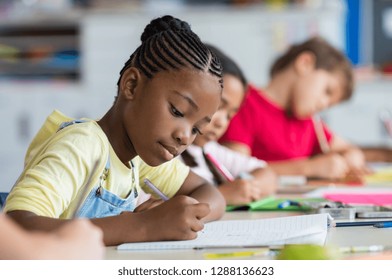 Cute pupil writing at desk in classroom at the elementary school. Student girl doing test in primary school. Children writing notes in classroom. African schoolgirl writing during the lesson. - Shutterstock ID 1288136623
