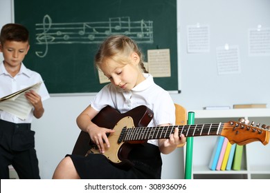 Cute Pupils Having Music Lesson In Classroom At Elementary School