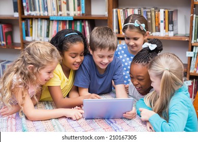 Cute pupils looking at tablet in library at the elementary school - Powered by Shutterstock