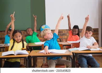 Cute pupils raising their hands at the elementary school - Shutterstock ID 210165823