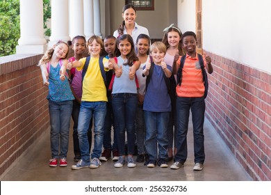 Cute Pupils Smiling At Camera In The Hall At The Elementary School