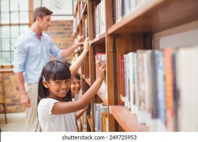 Cute pupils and teacher looking for books in library at the elementary school - Shutterstock ID 249725953