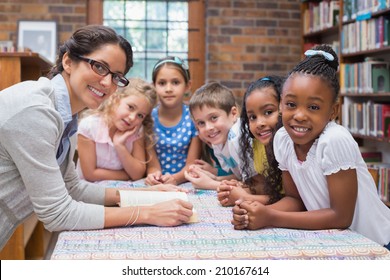 Cute Pupils And Teacher Reading In Library At The Elementary School