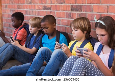 Cute pupils using mobile phone at the elementary school - Powered by Shutterstock