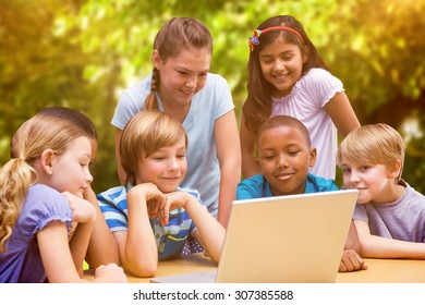 Cute pupils using tablet computer in library against trees and meadow in the park