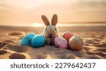 Cute rabbit toy and colorful painted easter eggs at the beach under sunshine. Shallow depth of field. Concept and idea of happy easter day.