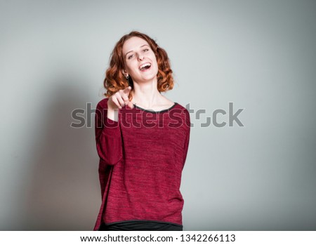 cute redhead girl making fun, isolated on gray background