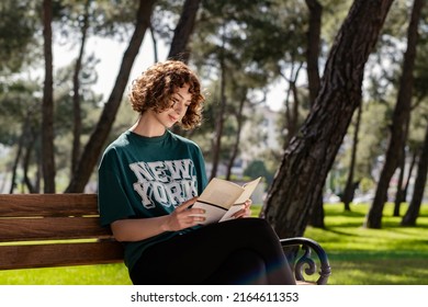 Cute Redhead Woman Wearing Casual Clothes Standing On City Park, Outdoor Sitting On Park Bench And Reading A Book. Self Improvement Concepts.