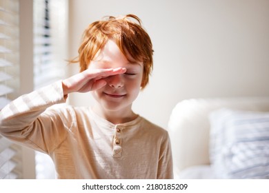 cute redhead young boy rubbing his eyes in the morning, waking up in sunlit bedroom - Shutterstock ID 2180185209