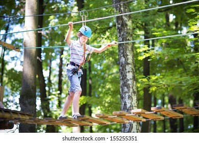 Cute School Boy Enjoying A Sunny Day In A Climbing Adventure Activity Park