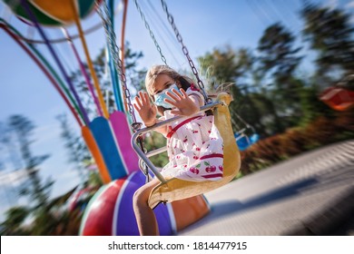 Cute School Girl Wearing Facial Mask Having Fun At An Amusement Park, New Reality During Covid Quarantine, Happy Anyway, Outdoor Summertime