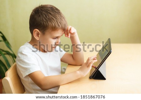 Cute schoolboy doing homework with computer at home. Child using gadgets for study. Education and distance learning concept. Homeschooling during quarantine. Stay at home entertainment.