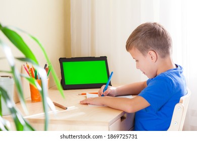 Cute schoolboy drawing picture, tablet with green screen stay on desk. Education and distance learning concept. - Powered by Shutterstock