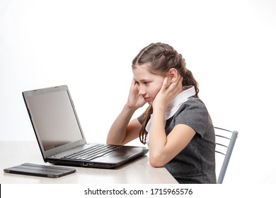 Cute schoolgirl is sitting at a laptop on a white background. Because of the epidemic, students from all over the world switched to distance learning. Children are studying a computer.