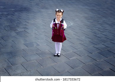 Cute Schoolgirl Wearing Uniform And School Bag Standing On The Empty School Yard, Looking Up. Shot From Above