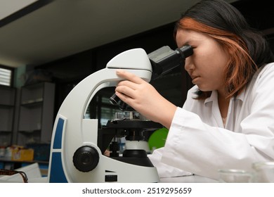 Cute scientist schoolgirl in lab coat looks through microscope for study microbiology in laboratory. Student girl child use lab equipment doing science experiment. Kid learning science education - Powered by Shutterstock