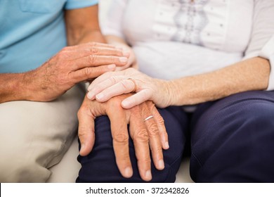 Cute Senior Couple Holding Hands On Sofa