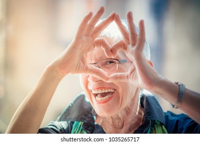 Una anciana de muy buen grado que está formando un corazón con sus manos y dedos