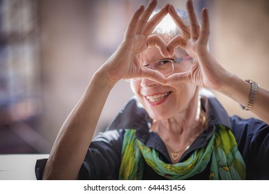 Mala anciana que está haciendo una forma cardíaca con sus manos y dedos