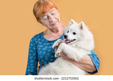 Cute Senior Older Woman Holding Her Favorite Pet Dog And Smiling, Focus On Dog's Eyes. Friendship Between A Dog And An Older Woman