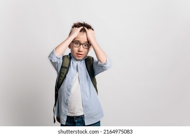 A Cute Serious Cheerful Asian 10 Year Old Teenager School Kid Boy In Glasses, Blue Shirt And Jeans With A Backpack Shocked Surprised Emotional, Isolated On White Background. Education Concept.