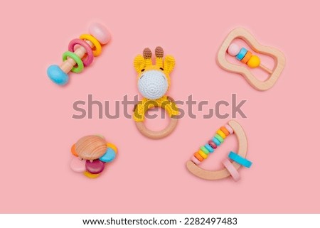 Cute set of wooden rattles for baby on pink background. Eco-friendly toys for newborns in the colors of the rainbow. Flat lay, top view.