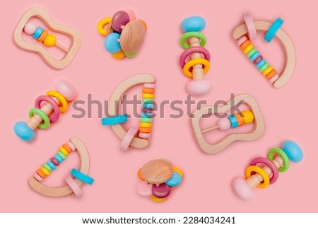 Cute set of wooden rattles for baby on pink background. Eco-friendly toys for newborns in the colors of the rainbow. Flat lay.