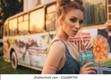 Cute sexy woman in jeans overall outfit with glitter freckles make up and hair buns. Summer evening in the city. Sensual posing