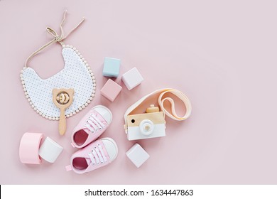Cute shoes, bib and wooden toys. Set of baby stuff and accessories for girl on pastel pink background.  Baby shower concept.  Fashion newborn. Flat lay, top view - Φωτογραφία στοκ