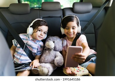 Cute Siblings Getting Along While Watching An Online Video On A Smartphone. Happy Brother And Sister Enjoying A Movie While Sitting In The Car 