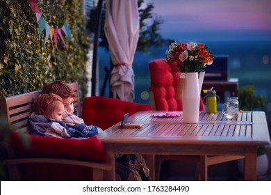 Cute Siblings Having Fun, Watching Cartoons On The Phone, Spending Time On Cozy Rooftop Patio On Summer Evening