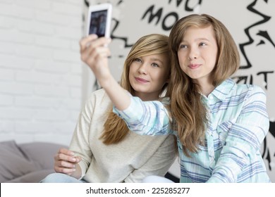 Cute sisters taking photos with smart phone at home
